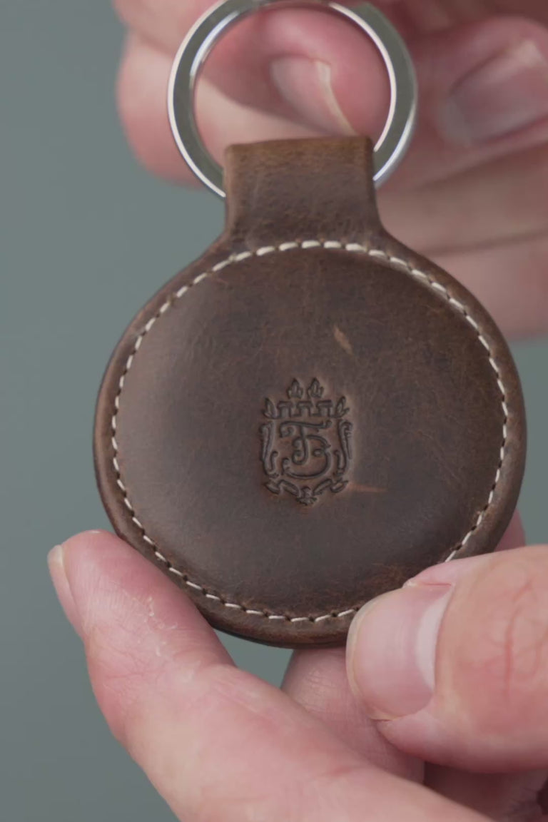 Looping video of a dark brown leather key fob. 