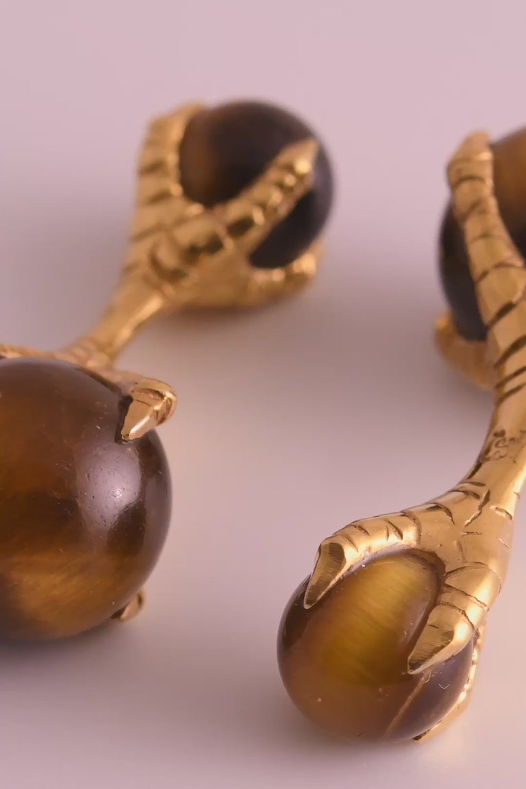 Looping video of yellow gold eagle claw cufflinks holding balls