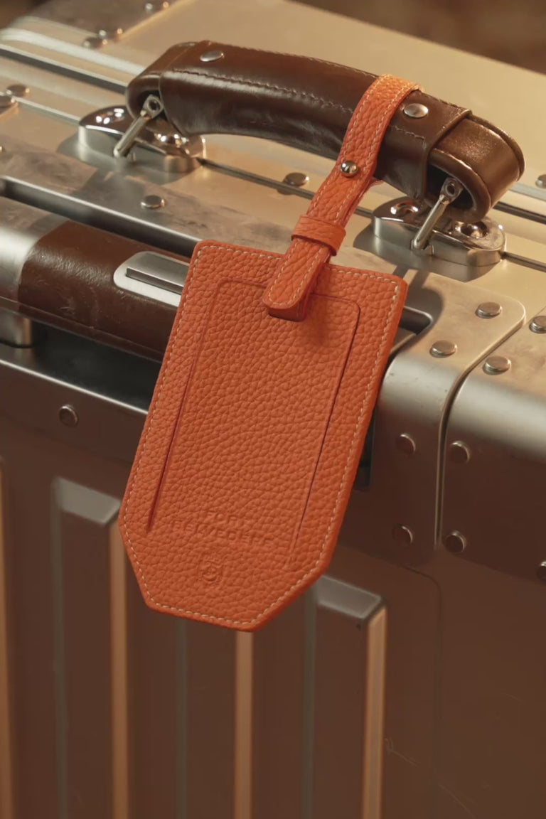 Looping video of a Fort Belvedere orange togo leather luggage tag