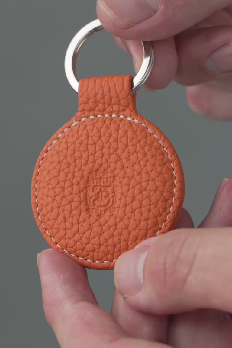 Looping video of an orange leather key fob. 